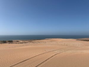 Un paysage côtier sablonneux avec des traces de pneus de quads et de buggys, idéal pour des excursions près d’Agadir.